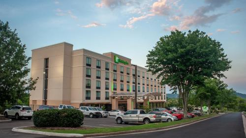a hotel building with cars parked in a parking lot at Holiday Inn Knoxville N - Merchant Drive by IHG in Knoxville