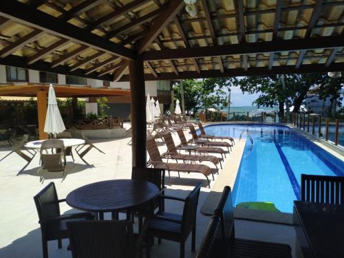 um grupo de cadeiras e mesas ao lado de uma piscina em Porto Dream Praia do Forte em Mata de São João