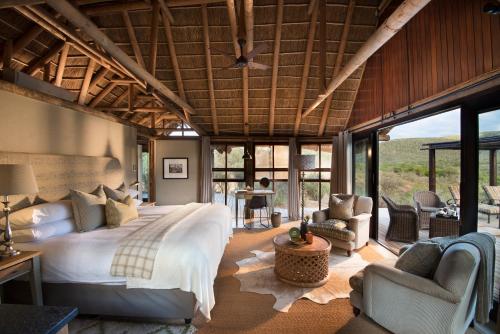 a bedroom with a large bed in a room with windows at Kwandwe Great Fish River Lodge in Grahamstown