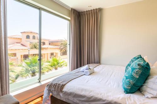 Un dormitorio con una gran ventana con un osito de peluche en la cama en da Heim Guest House, en Ciudad del Cabo