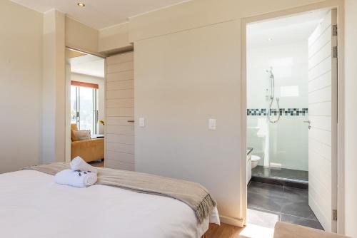 Un dormitorio con una cama blanca y un baño. en da Heim Guest House, en Ciudad del Cabo