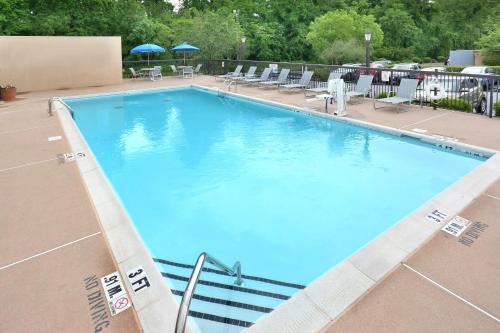a large blue swimming pool with chairs and umbrellas at Holiday Inn Express Raleigh-Durham Airport by IHG in Morrisville
