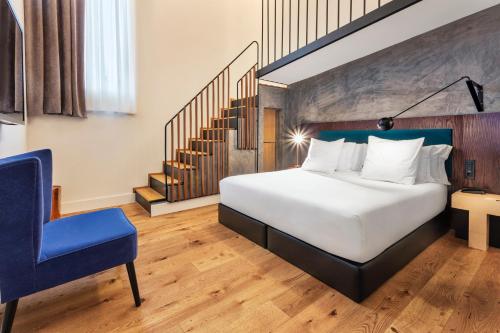 a bedroom with a bed and a blue chair at One Shot Tabakalera House in Donostia-San Sebastián