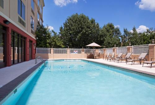 a swimming pool with chairs and a building at Holiday Inn Express Murfreesboro Central, an IHG Hotel in Murfreesboro