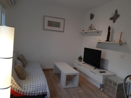 a white living room with a tv and a couch at Apartamento de la huerta in Murcia