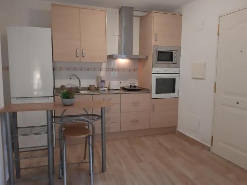 a kitchen with white cabinets and a table with a chair at Apartamento de la huerta in Murcia