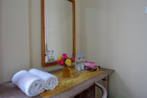 a bathroom with a sink with towels and a mirror at RedDoorz @ Hotel Aulia Majene in Majene