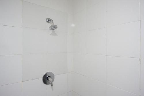 ducha con pared de azulejos blancos y cabezal de ducha en RedDoorz @ Hotel Grand Aulia Majene, en Majene