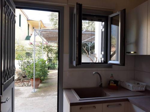 eine Küche mit einem Waschbecken und einem Fenster in der Unterkunft Garden's Home 2 in Leonidi