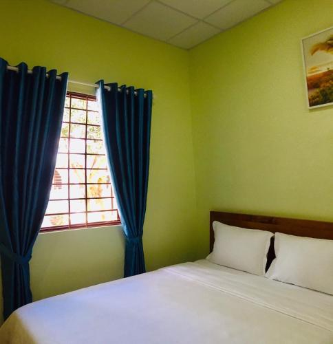 a bedroom with a bed with blue curtains and a window at Eden House & Coffee Con Dao in Con Dao