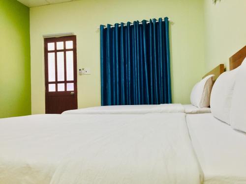 a bedroom with two beds and a blue curtain at Eden House & Coffee Con Dao in Con Dao