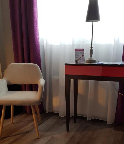a desk and a chair next to a table with a lamp at Hotel de Champagne in Épernay