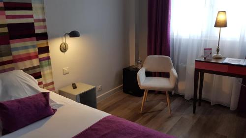 a bedroom with a bed and a desk and a chair at Hotel de Champagne in Épernay