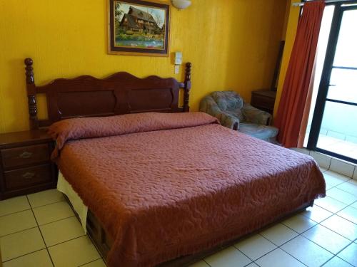 a bedroom with a bed with a red comforter at Hotel Real Jojutla in Jojutla de Juárez