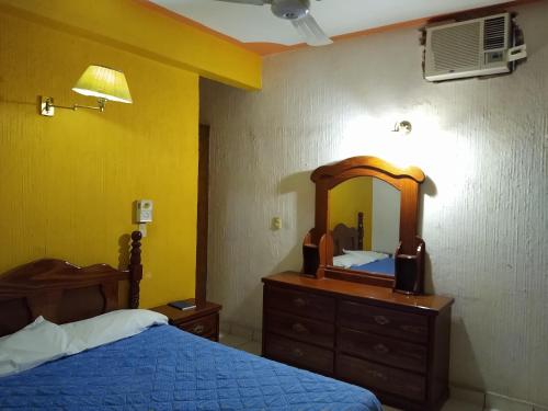 a bedroom with a bed and a dresser with a mirror at Hotel Real Jojutla in Jojutla de Juárez