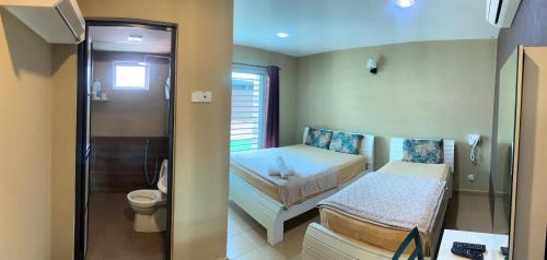 a small room with two beds and a toilet at Hotel Rasa Sayang Artisan Inn Jelebu in Kampong Seperi