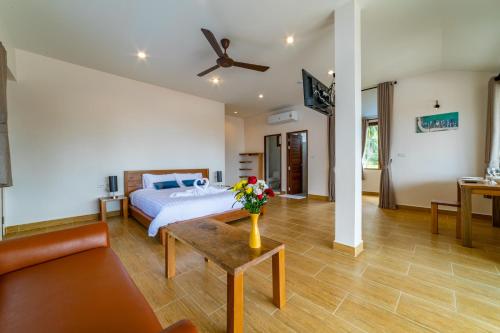 een slaapkamer met een bed en een vaas met bloemen op een tafel bij Le Grand Bleu Hotel in Wok Tum