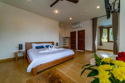 ein Schlafzimmer mit einem Bett und Blumen in einem Zimmer in der Unterkunft Le Grand Bleu Hotel in Wok Tum