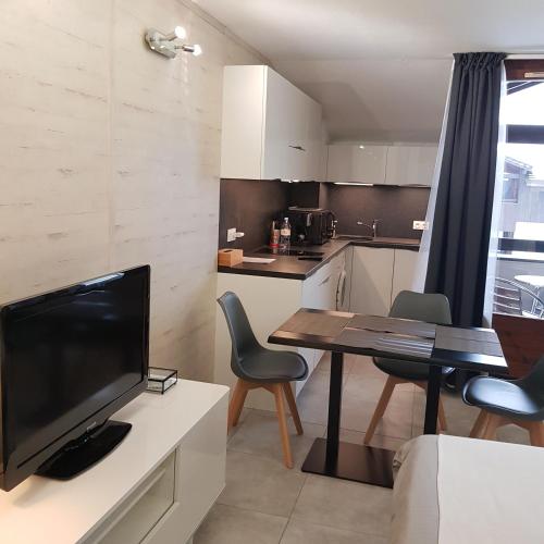 - une petite cuisine avec une table et une télévision dans la chambre dans l'établissement STUDIO 28 m2 TOUT CONFORT NEUF LABEL 3 ETOILES 4 PERSONNES CYBELE, à Brides-les-Bains