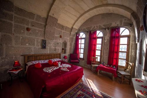 a bedroom with a red bed in a castle at Kapadokya Ihlara Konakları Otel Konak Odaları in Guzelyurt