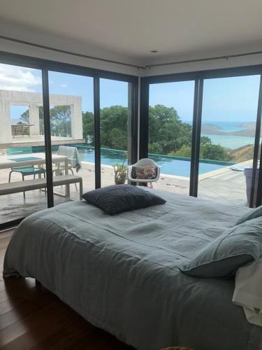 a bedroom with a bed and a view of a pool at Villa Californienne proche Nouméa in Païta