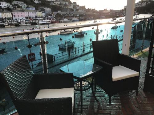 a balcony with chairs and a table and a view of a harbor at Shellseekers Guest House in Looe