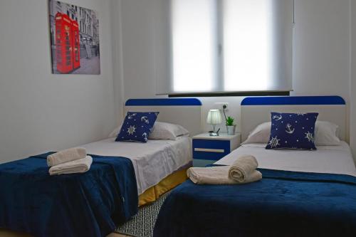 ベルレガートにあるAnacasa Migjorn Mar de Bellreguard AP3のベッドルーム1室(青と白のシーツが備わるベッド2台付)