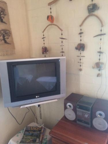 a tv sitting on a shelf next to a table at Haus Barbara Guest House in Bredasdorp