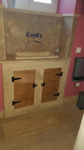 een badkamer met twee houten deuren en een wastafel bij Gîte La P'tite Louise in Les Riceys