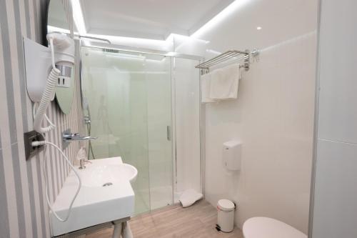 a white bathroom with a shower and a sink at Apartamentos Abril in Nerja