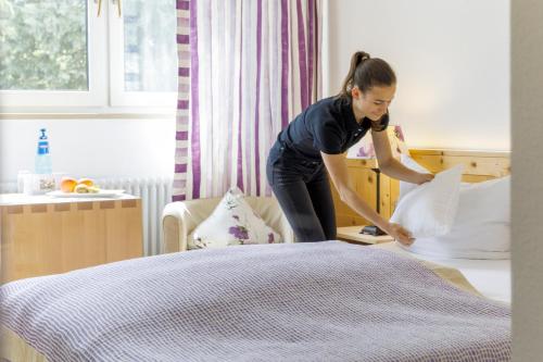 a woman is making a bed in a bedroom at Schlegelhof in Kirchzarten