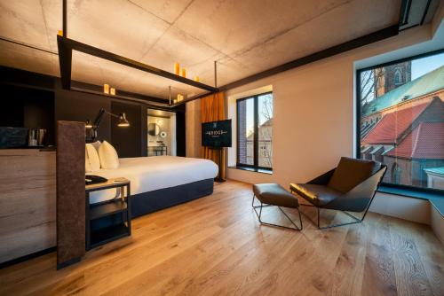 a hotel room with a bed and a chair at The Bridge Wroclaw - MGallery in Wrocław