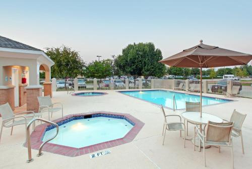 a swimming pool with a table and chairs and an umbrella at Holiday Inn Express Hotel and Suites DFW-Grapevine by IHG in Grapevine