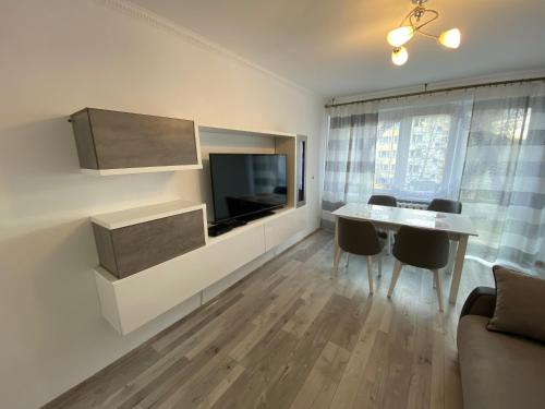 a living room with a television and a table and chairs at Apartament Zacisze in Ustrzyki Dolne