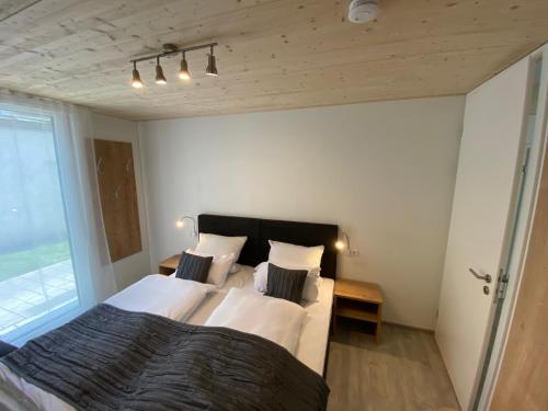 una camera da letto con un grande letto con lenzuola e cuscini bianchi di Ferienwohnung Preisinger a Oberammergau