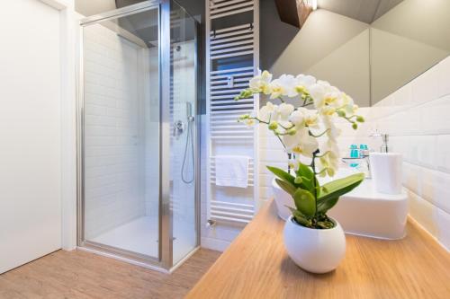 a bathroom with a shower and a vase with white flowers at Aqualago casa vacanze Suite in Verbania