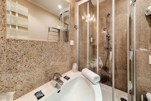 a bathroom with a shower and a sink and a tub at Grand Royal Hotel in Poznań