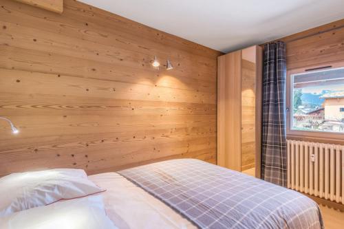 a bedroom with a wooden wall with a bed at Appartement Hibou - Welkeys in Megève