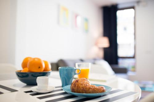 a table with a plate of food and a glass of orange juice at Oceanográfico Apartments in Valencia