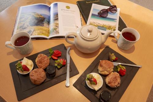 a table with two plates of food and a book at Beachcombers Apartments in Newquay