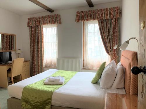 a bedroom with a bed and a desk and two windows at Ye Olde House in Shepperton