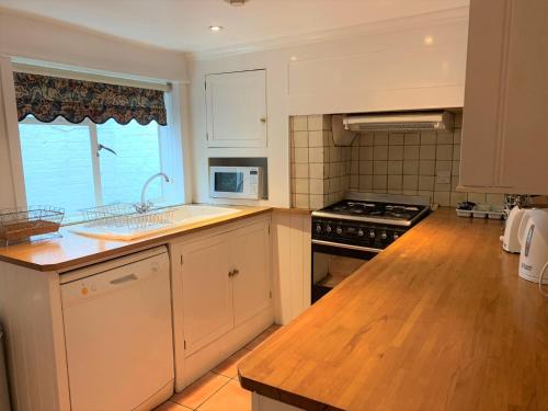 a kitchen with a sink and a stove top oven at Ye Olde House in Shepperton