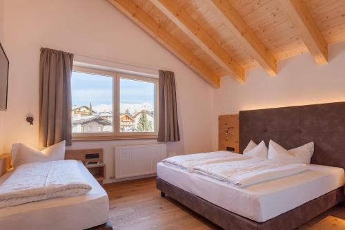 a bedroom with two beds and a large window at Apart-Hotel Dreisonnenhof in Fiss