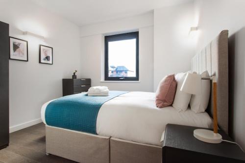 a bedroom with a large bed and a window at Abbott House by Viridian Apartments in St. Albans