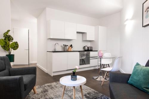 a living room with a couch and a kitchen at Abbott House by Viridian Apartments in Saint Albans