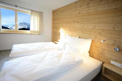 two beds in a bedroom with a wooden wall at Birklstüberl Restaurant und Appartement in Seefeld in Tirol