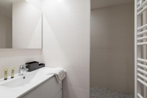 een witte badkamer met een wastafel en een spiegel bij HONORÊ - SUITE ARBRE SEC in Lyon