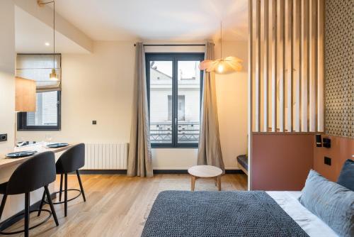 Cette chambre comprend un lit, une table et un bureau. dans l'établissement HONORÊ - SUITE ARBRE SEC, à Lyon