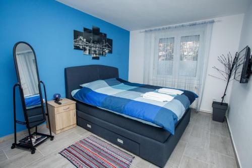 Dormitorio azul con cama y espejo en 7 Days Premium Apartment en Subotica