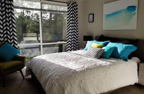 a bedroom with a bed with pillows and a window at Ferny Hill Retreat, Emerald Victoria in Emerald